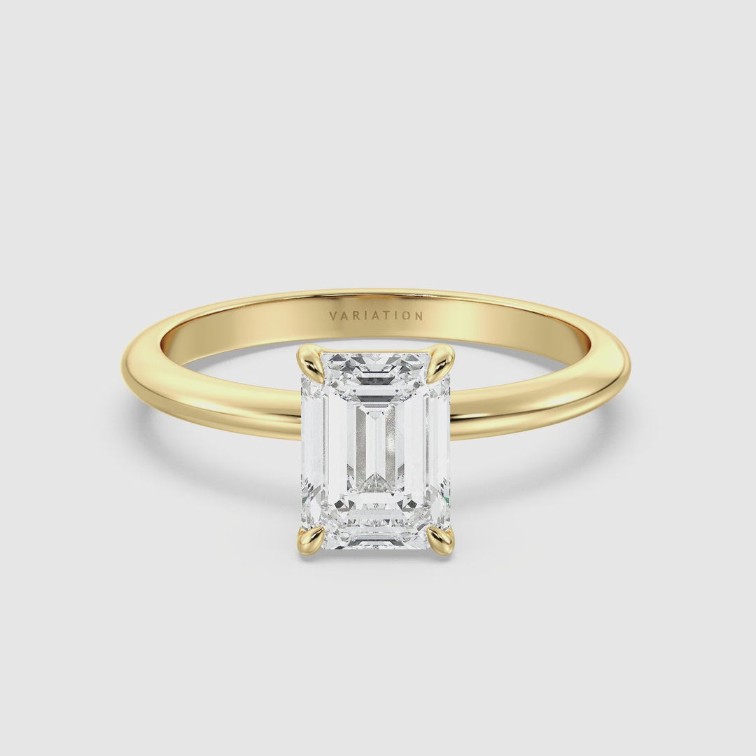 A video showcasing an Emerald Cut Lab-Grown Diamond Solitaire Engagement Ring in 18K Yellow Gold. The video highlights the elegant emerald cut diamond, securely held by a 4-claw prong setting, with the ring rotating to display its intricate craftsmanship and luxurious yellow gold band