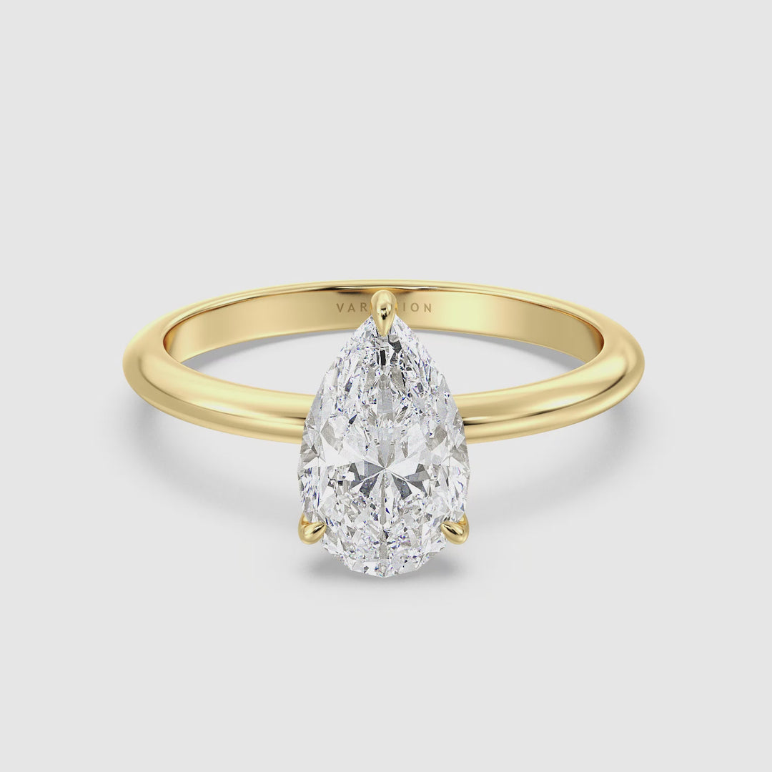 Close-up video of the Timeless 3-Claw Pear Cut Lab-Grown Diamond Solitaire Engagement Ring in 18K Yellow Gold. The video highlights the exquisite pear-cut diamond, its brilliance enhanced by a classic three-claw prong setting, and the warm, luxurious tone of the yellow gold band.